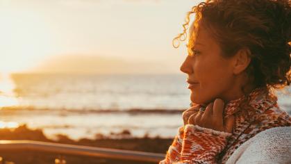 lady dreaming and thinking outdoor with ocean beach and sunset light in background