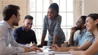 Cheerful woman interacting with colleagues at meeting table