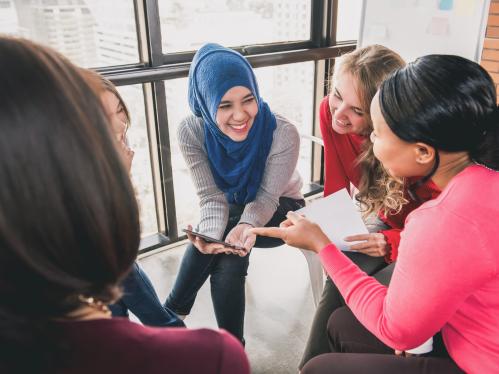 Women from diverse background sitting on chairs smiling and talking